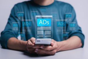 digital marketing and online advertising to targeted customers shooting ads on cross feeds to optimize customer engagement person using mobile smartphone with virtual screen of ads on website